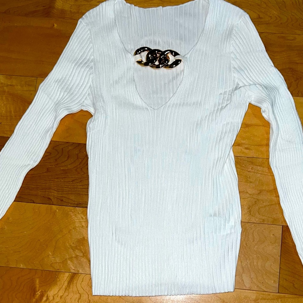 White sweater, with gold chain accessory, has lots of stretch